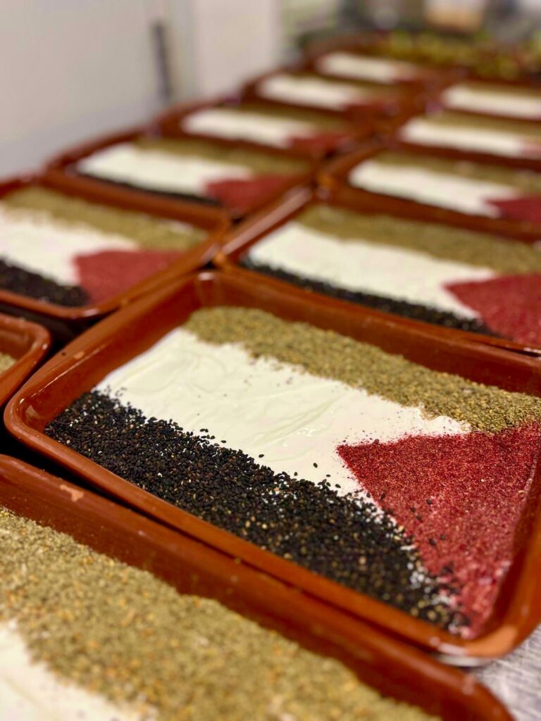 Op deze foto staat de eerder genoemde labneh-vlag. De labneh zit in een stenen aarden schotel, en met verschillende kruiden is er de palestijnse vlag op getekend.