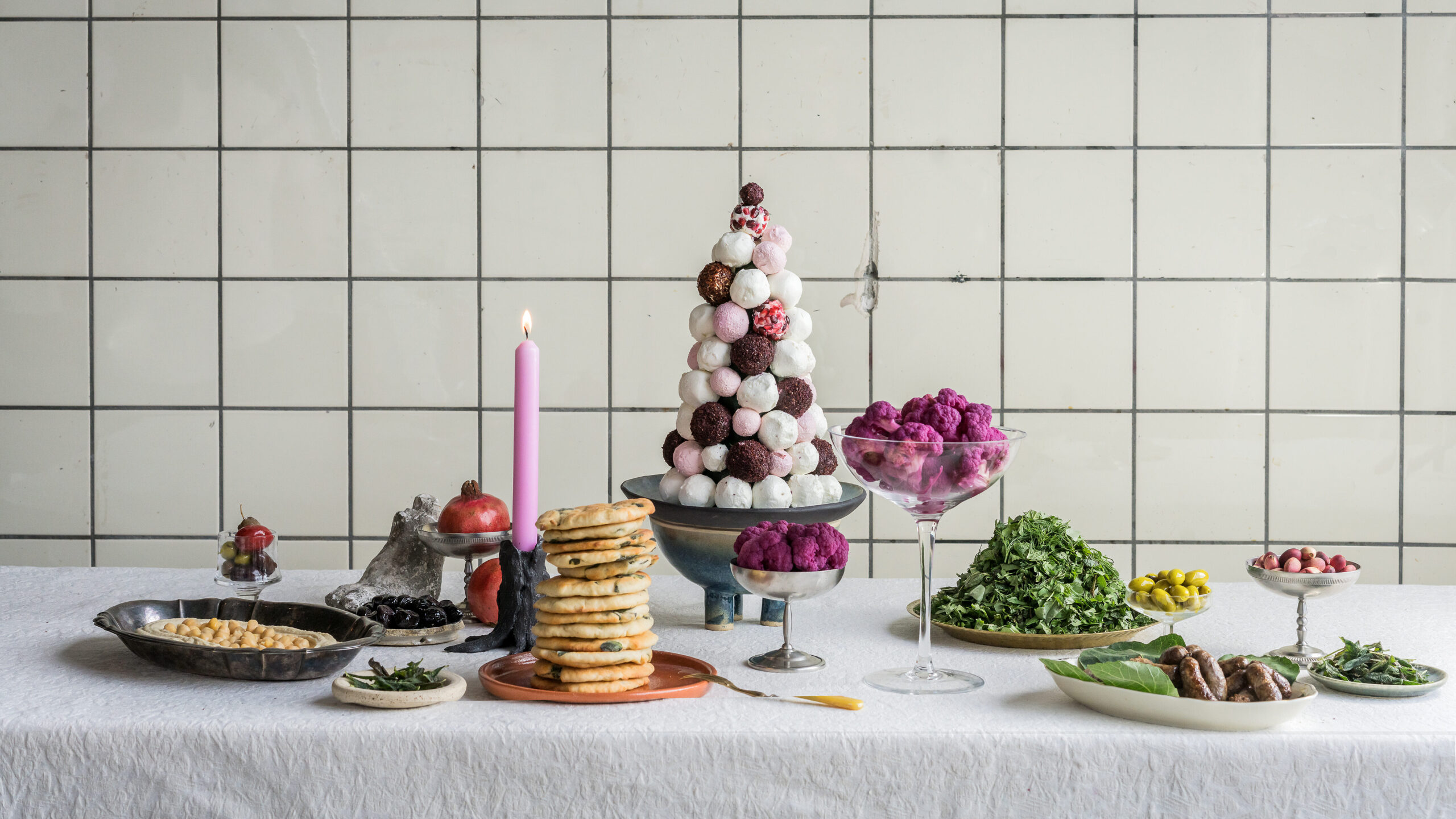 Een prachtig opgemaakte tafel met verschillende gerechten op een wit tafelkleed voor een witte tegelmuur