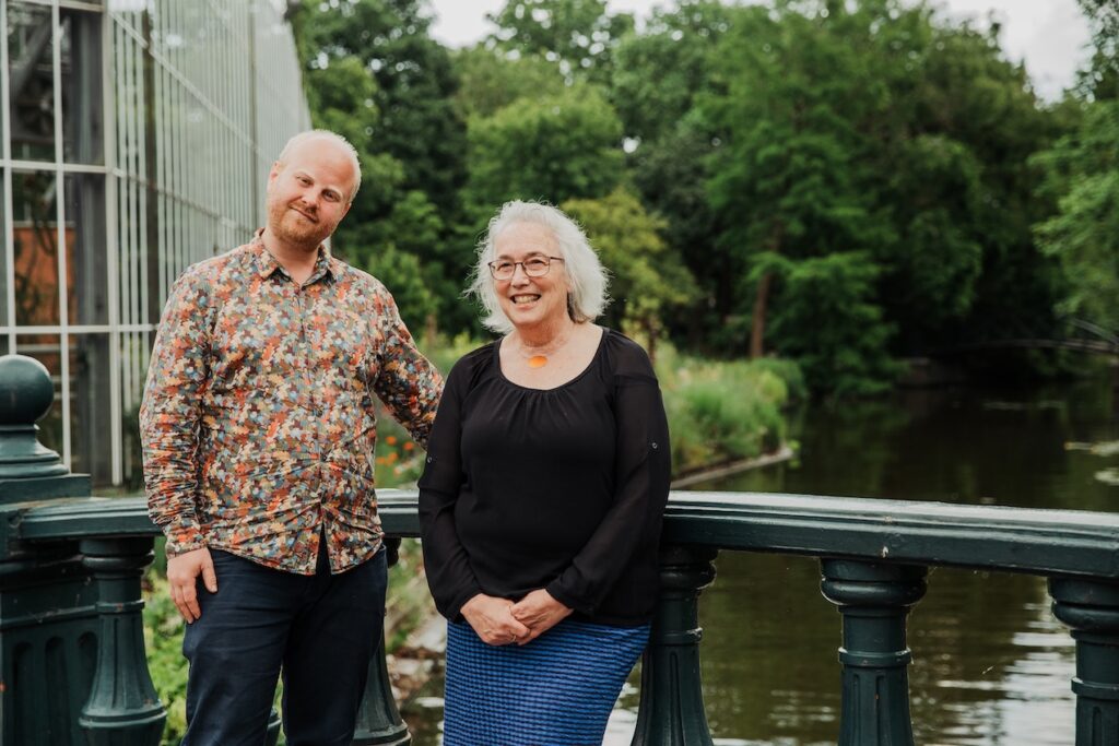 Job van den Assem en Sandra Ball leunen tegen een ouderwetse brugleuning en kijken glimlachend in de camera.