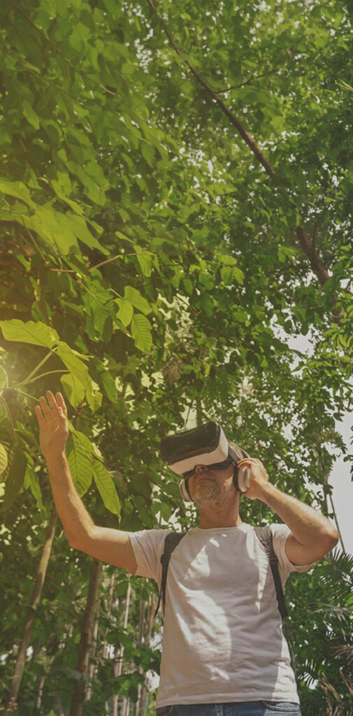 Foto van iemand met een VR bril op die door een bos loopt. 
